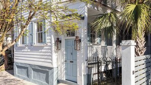 A white building with a light blue door, a small porch, and a black wrought iron gate. - Casa Zoë | Cabana House – Bold Design, Prime Location (Charleston)