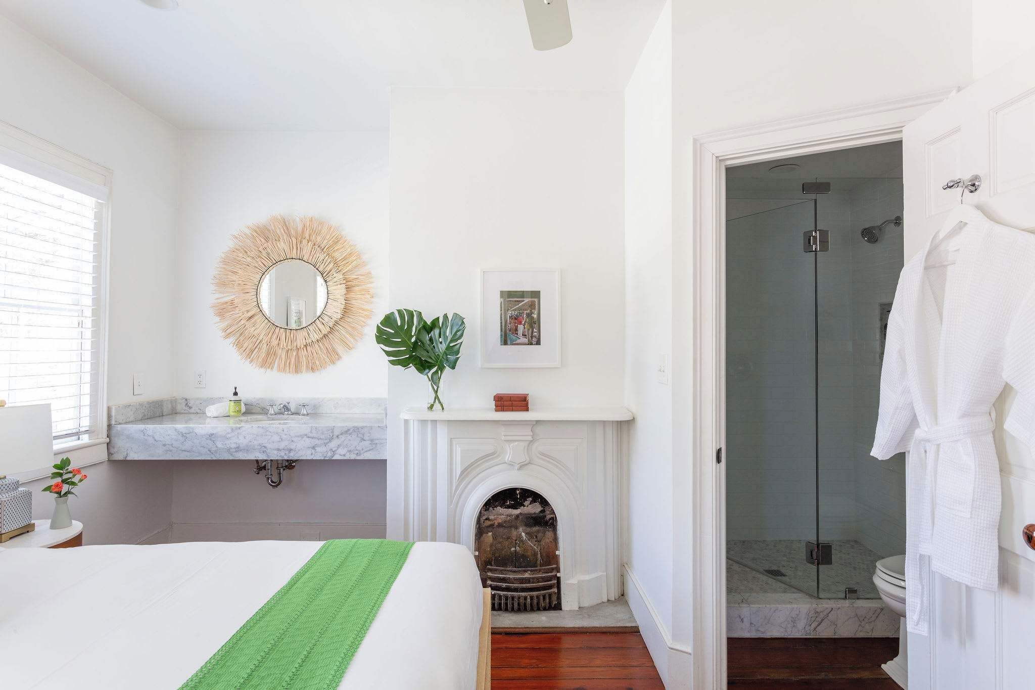 A bedroom with a bed, a vanity with a mirror, a fireplace, and a walk-in closet with a robe hanging.