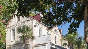 A two-story building with a white facade, a red roof, and a front porch.