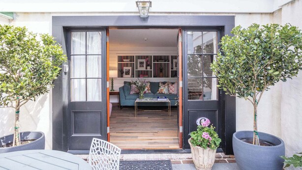 A modern entrance with a dark door, a small table, and two potted plants.