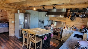 A kitchen with wooden walls, a stainless steel stove, and a marble countertop. - Luxury Log Home at Foot of Mt. Princeton (Buena Vista)