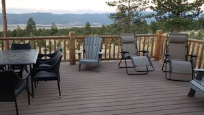 A deck with outdoor furniture, including a table and chairs, overlooking a scenic landscape with mountains and trees. - Luxury Log Home at Foot of Mt. Princeton (Buena Vista)