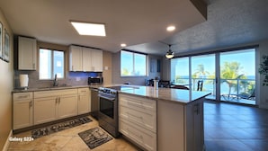 Cocina moderna con una isla central, electrodomésticos integrados y amplias ventanas con vistas al océano.