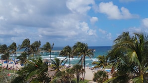 Una playa con palmeras, un muelle y el océano.