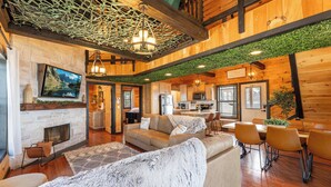 A spacious living area with a fireplace, a sofa, and a dining table with chairs. - Sunset Ridge cabin 21 miles from Chatt, TN! Indoor pool & hot tub! (Bryant)