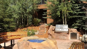 Un espace extérieur aménagé avec une terrasse, un barbecue, des sièges et un petit élément décoratif aquatique.