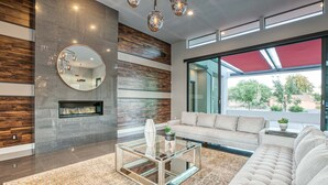Una sala de estar moderna con un tapete estampado con diseño de piedra, una mesa de centro de vidrio, un sofá color beige y una chimenea.