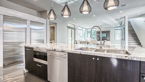Una cocina moderna con una isla grande, electrodomésticos de acero inoxidable e iluminación colgante.