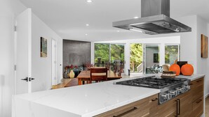 Uma cozinha moderna com uma ilha grande, armários de madeira e um exaustor de aço inoxidável.