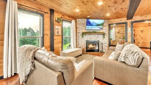 A cozy living room with a fireplace, leather sofas, and a stone wall. - Pop & Granny's cabin with a fire pit, hot tub, & indoor pool! (Bryant)