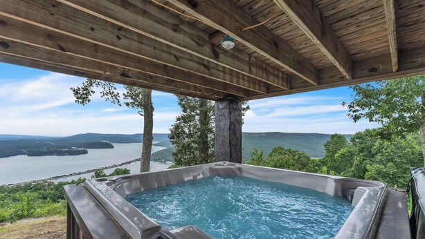 A hot tub with a wooden roof and a view of a lake and mountains. - Pop & Granny's cabin with a fire pit, hot tub, & indoor pool! (Bryant)