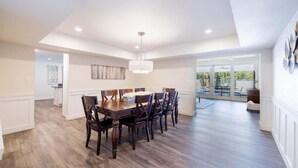 Un comedor amplio con una mesa y sillas de madera, una lámpara colgante y vistas al exterior.