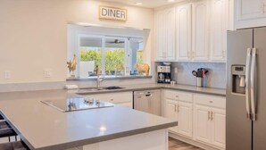 Una cocina moderna con armarios blancos, una isla grande y un letrero que dice 'DINER'.