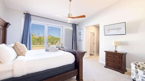 Un dormitorio con una cama grande, un ventilador de techo, un aparador y un cartel enmarcado en la pared.