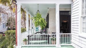 A white building with a covered porch, columns, and potted plants. - Casa Zoë | Elegant 3BR Retreat Near King Street (Charleston)
