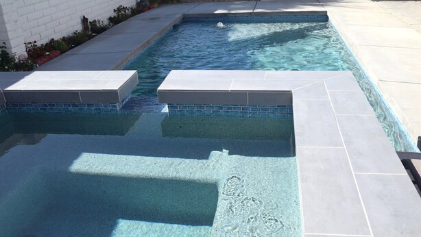 A swimming pool with clear blue water, surrounded by a tiled deck and a brick wall. - West Racquet Club Art Hall (Palm Springs)