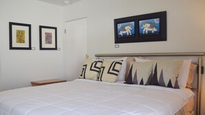 A neatly made bed with a white duvet, a metal headboard, and two framed artworks above it. - West Racquet Club Art Hall (Palm Springs)