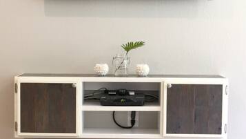Un salon moderne avec un téléviseur à écran plat fixé au mur, un meuble en bois en dessous et un plateau décoratif posé sur le sol.