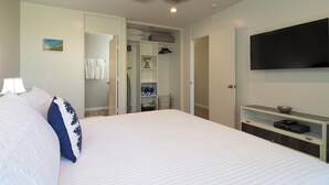 Een slaapkamer met een bed, een televisie, een plafondventilator en een inloopkast.