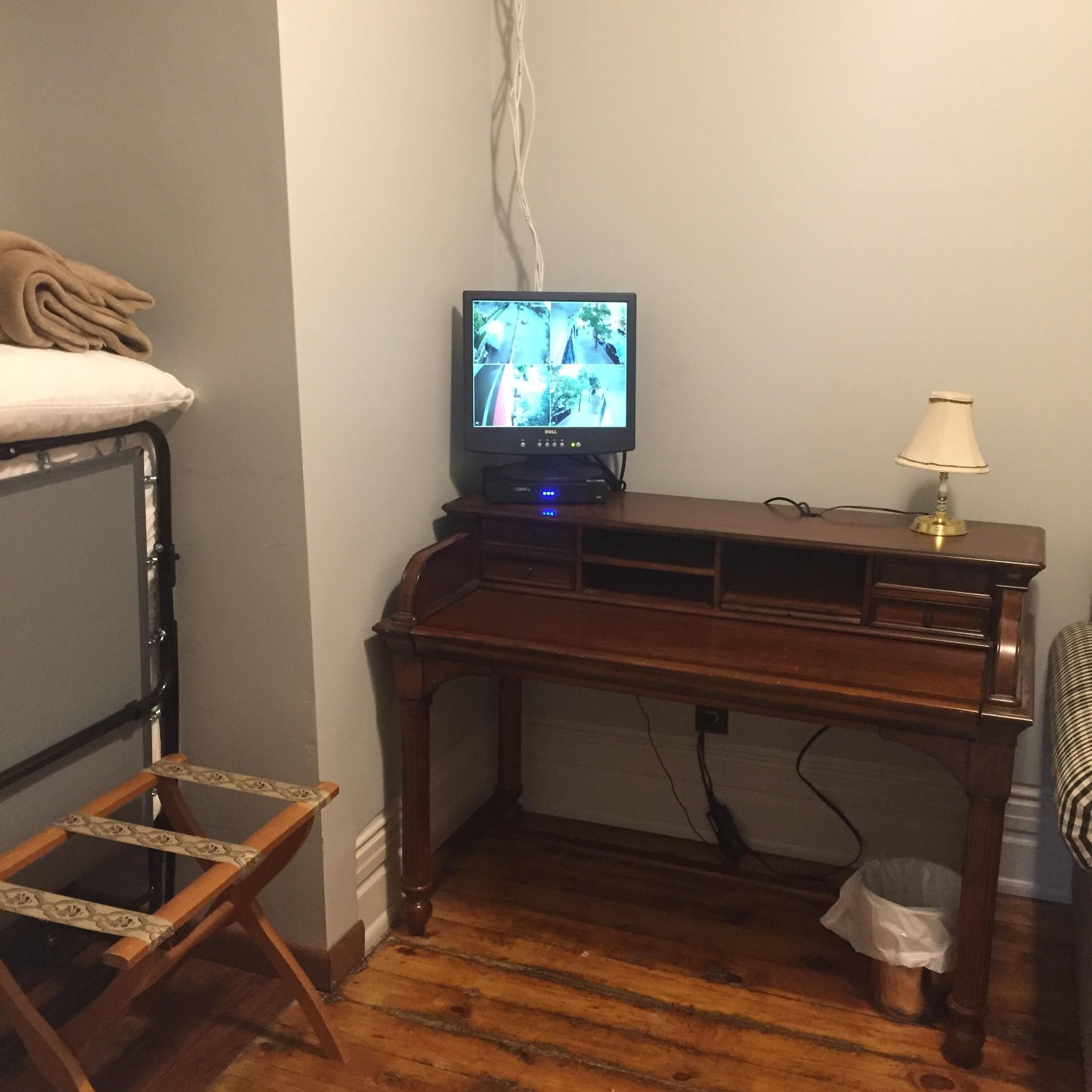 Una habitación pequeña con una cama nido, un escritorio con una computadora y una lámpara.