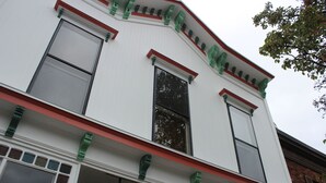 Um edifício com fachada branca, detalhes verdes e várias janelas.