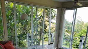 Un salón amplio con un gran ventanal que da a un jardín exuberante.