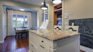 Una cucina con un piano di lavoro in granito, mobili bianchi e una lavagna con le informazioni su WiFi.