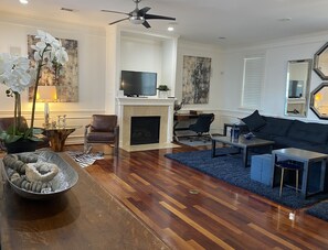Uma sala de estar com lareira, televisão, sofá e mesa de centro.
