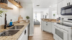 Una cocina moderna con encimeras de granito, electrodomésticos de acero inoxidable y armarios blancos.