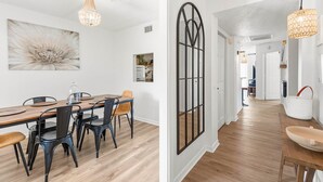 Un comedor con una mesa de madera, sillas negras y una lámpara de araña.