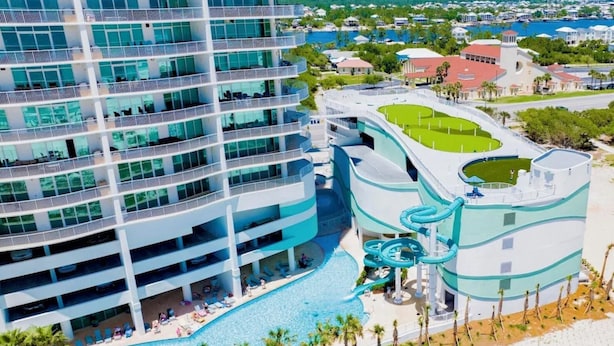Et hotel med flere etager, stor swimmingpool, vandrutsjebaner og en strand.