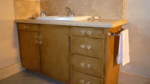 A bathroom with a sink, mirror, and wooden cabinet drawers.