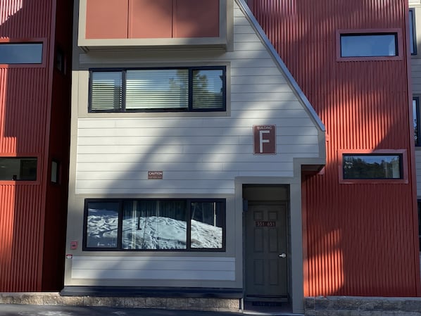 A building with a 'Caution' sign, a 'Building F' sign, and a door with the number '551 651'.