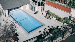Piscina no terraço com superfície de água azul cristalina, rodeada por área de estar externa e um espaço coberto com telhado inclinado.