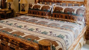 Quarto com cama grande, ventilador de teto, pintura de um elefante e cabeceira de madeira.