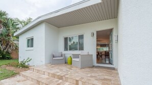 Ein modernes Haus mit einer Terrassenanlage, inklusive einer Couch und einem kleinen Tisch.