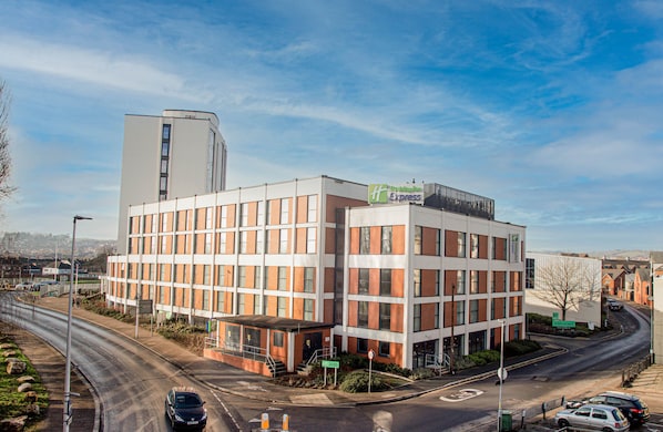 A modern hotel with a prominent 'Hilton Express' sign, featuring a brick facade and a flat roof.