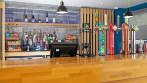 A bar area with a wooden counter, various liquor bottles, and a coffee machine. - Holiday Inn Express Exeter - City Centre by IHG (Exeter)