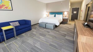 Una habitación de hotel con una cama, un sofá azul, una mesita y un escritorio.