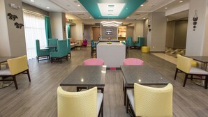 Un vestíbulo de hotel con una isla central, zonas de estar y una recepción.