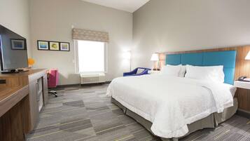 A hotel room with a bed, desk, chair, and a television.
