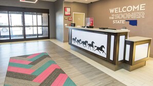 A reception desk with a "Welcome to the Sooner State" sign, a fire extinguisher, and a framed picture on the wall.