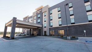 A modern hotel with a covered entrance, a clear sign indicating a 12-foot clearance, and a parking area with a handicapped parking sign.