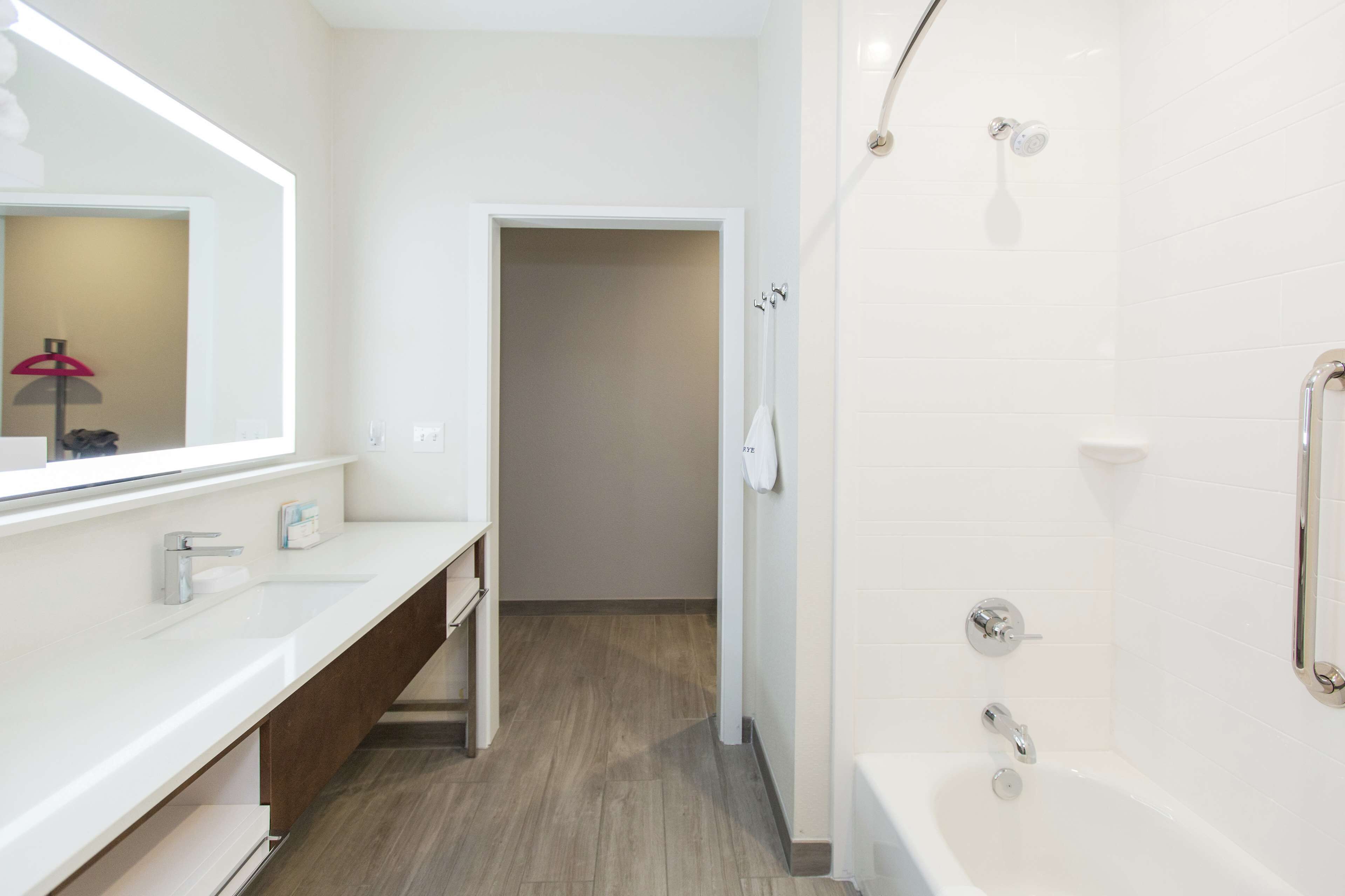 Un baño moderno con lavamanos, espejo y ducha blancos.