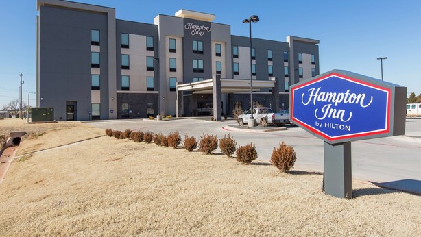 A modern Hampton Inn by Hilton building with a clear entrance and a parking area.