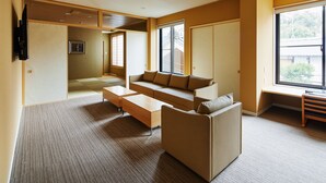 A modern living room with a sofa, coffee table, and a TV mounted on the wall. - Onsen No Yado Gion Maisen Bettei (Kyoto)