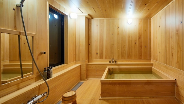 A wooden sauna room with a large bathtub, a showerhead, and a mirror. - Onsen No Yado Gion Maisen Bettei (Kyoto)