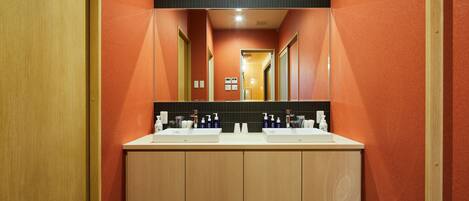 A modern bathroom with two sinks, wooden cabinets, and a mirror above.