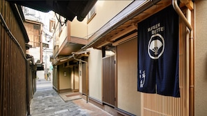 A narrow alleyway with traditional wooden buildings, a tatami mat floor, and a hanging banner with Japanese text. - Onsen No Yado Gion Maisen Bettei (Kyoto)