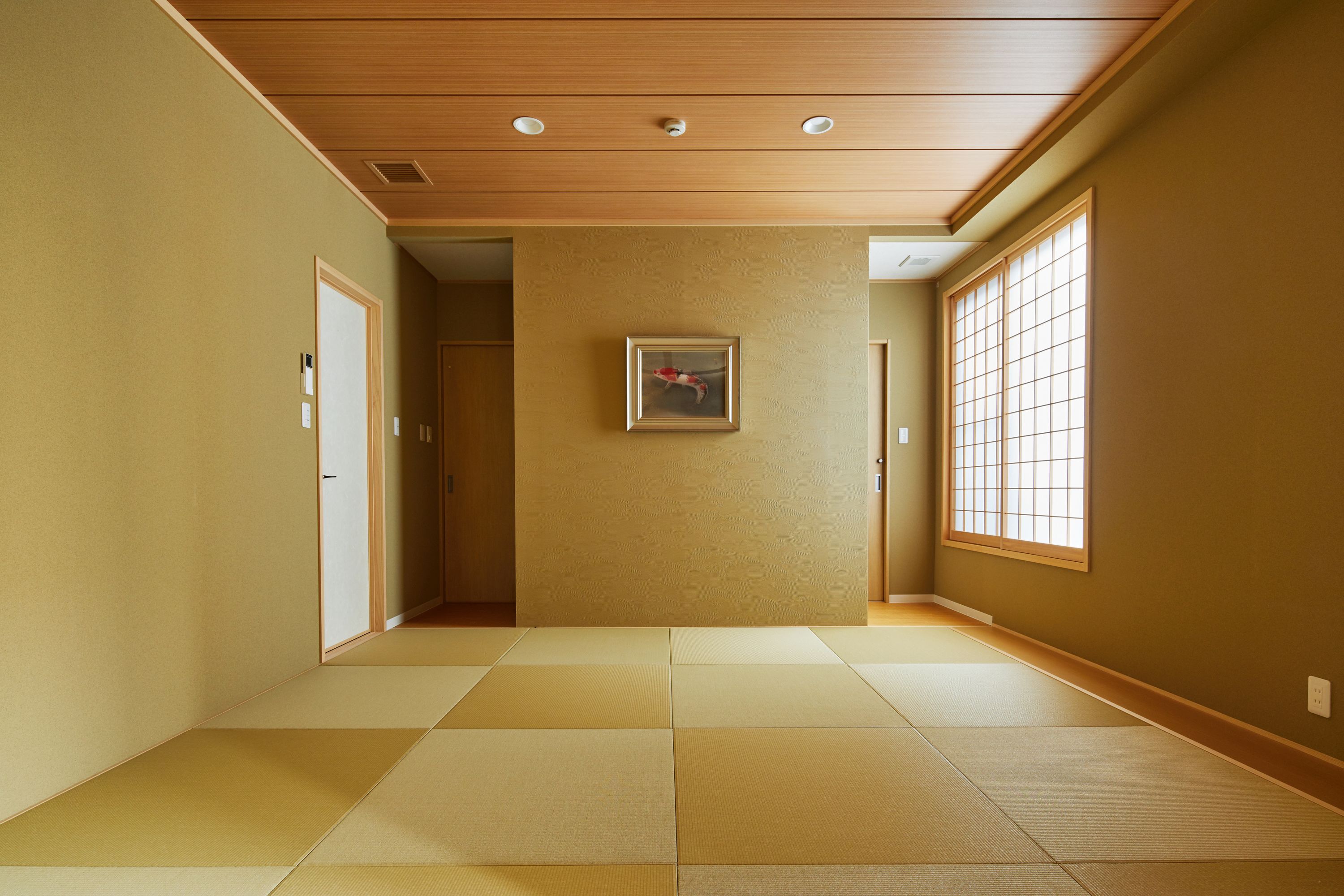 Un pasillo con suelo de tatami, techo de paneles de madera y un cuadro enmarcado en la pared.